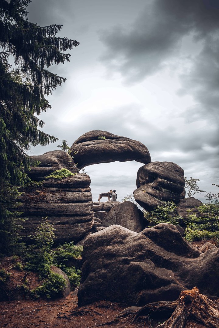 Člověk se psem sedící ve skalní bráně